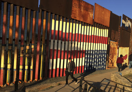 People pass graffiti along the border structure  in Tijuana, Mexico, Wednesday, Jan. 25, 2017.  President Donald Trump moved aggressively to tighten the nation's immigration controls Wednesday, signing executive actions to jumpstart construction of his promised U.S.-Mexico border wall and cut federal grants for immigrant-protecting "sanctuary cities." (AP Photo/Julie Watson)