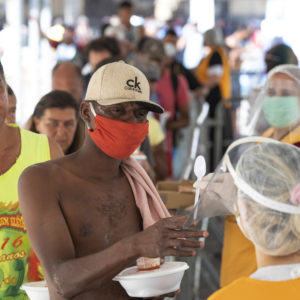Volunteers from a christian church give food to homeless people during a quarantine imposed by the state government to help stop the spread of the new coronavirus in Sao Paulo, Brazil, Monday, April 27, 2020. (AP Photo/Andre Penner)