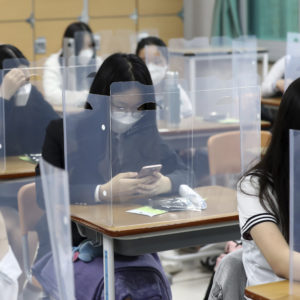Senior students wait for class to begin with plastic boards placed on their desks at  Jeonmin High School in Daejeon, South Korea, Wednesday, May 20, 2020. South Korean students began returning to schools Wednesday as their country prepares for a new normal amid the coronavirus pandemic. (Kim Jun-beom/Yonhap via AP)