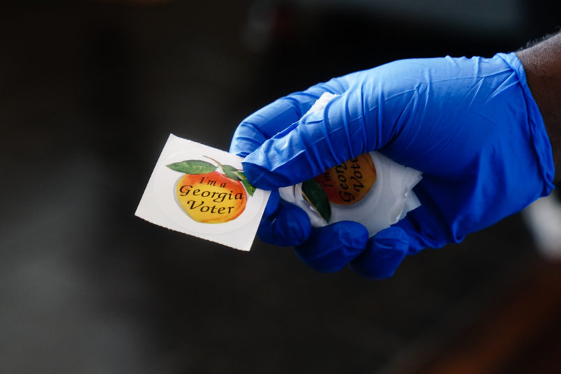 ATLANTA, GA - JUNE 09: A polling place worker holds an "I'm a Georgia Voter" sticker to hand to a voter on June 9, 2020 in Atlanta, Georgia. (Photo by Elijah Nouvelage/Getty Images)